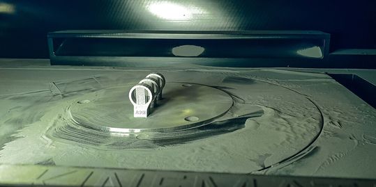 Mittels einem 3D-Druckverfahren wird der Ring hergestellt. Mittendrin wird der Prozess angehalten: Ein automatisiertes Robotersystem platziert die Elektronik, bevor der Druckprozess weitergeht. (Bild:  Fraunhofer IGCV)