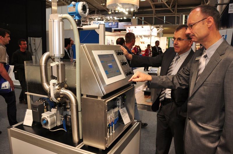 Dr. Roos, Leiter Prozessautomation bei Festo (links), und Dr. Wolfgang Rieger, Key Account Manager bei Festo, erklären auf der IFAT anhand eines Exponats die Vorteile der pneumatischen Automatisierung von Wasseraufbereitungsanlagen. Für die Messe wurde eine Automatisierungslösung im kleinen Maßstab nachgebaut, die derzeit in Ägypten in Betrieb genommen wird. (M. Henig) (Archiv: Vogel Business Media)