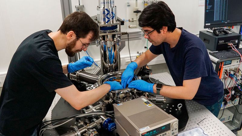 David Walther (links) und Carlos Rincon, wissenschaftliche Mitarbeiter am Lehrstuhl für Werkstoffe und Zuverlässigkeit mikrotechnischer Systeme der Technischen Universität Chemnitz, installieren einen neuen Prüfstand im Inneren der Kammer eines Helium-Kryostaten.(Bild:  TU Chemnitz)