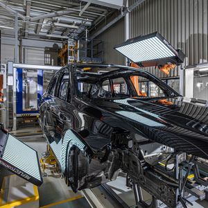 Um zu ermitteln, wo sich Fehler im Lack befinden, projizieren große Monitore schwarz-weiße Streifenmuster auf die Fahrzeugoberfläche. Kameras scannen die Oberfläche und erkennen Veränderungen im spiegelnden Lack.(Bild:  Harry Zdera/BMW)