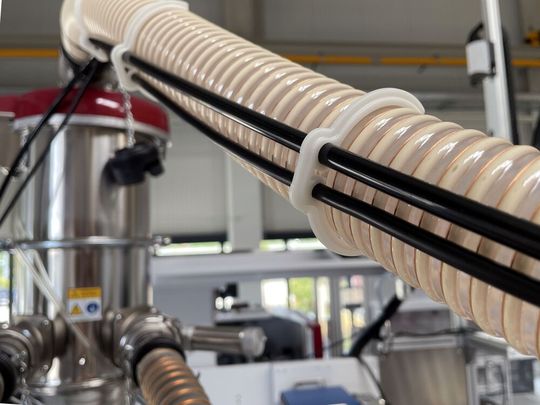 Eine Klammer, die der Verschwendung von üblichen Klemmsystemen entgegentritt, hat Wittmann für die Fakuma als Highlight geplant. Sie nennt sich Ecofritz (helles Kunstststoffteil) und wird auf der Messe gefertigt, was außerdem sehr nachhaltig klappt. Aber es gibt noch mehr ...(Bild:  Wittmann)