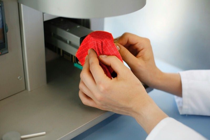 Bei der Überprüfung der Kontaktwärme wird das Prüfmaterial einer Temperatur von 250 °C ausgesetzt. (Bild: Hohenstein Institute)