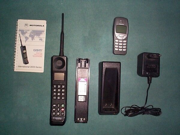 Ein Mobiltelefon Motorola International 3200 (unten) mit Handbuch und Ladegerät im Vergleich zum 2G-Mobiltelefon Nokia 3210 (Bild: Volker Artmann/Creative Commons Attribution-Share Alike 2.5 Generic license)