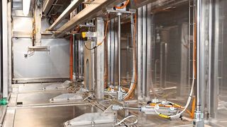 Bei der individuell gebauten Reinigungsanlage von Purima nimmt ein Greifer den Korb auf und transportiert ihn zur nächsten Station. (Purima)