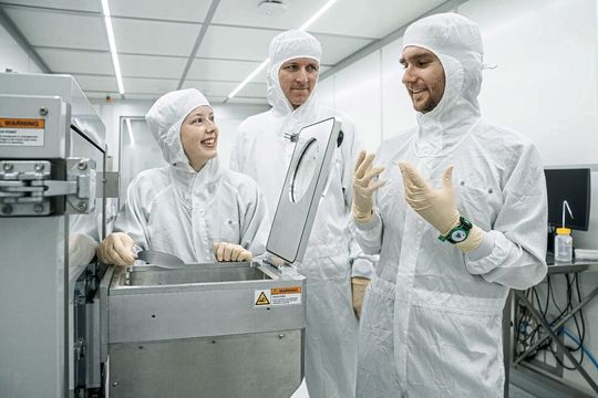Lauren Riddiford, Aleš Hrabec et Jeffrey Brock (de gauche à droite) dans la salle blanche du Park Innovaare, juste à côté du PSI. C'est ici que sont créées les nouvelles structures magnétiques, qui sont modifiées de manière ciblée au laser. (Source :  Institut Paul Scherrer PSI/ Mahir Dzambegovic)
