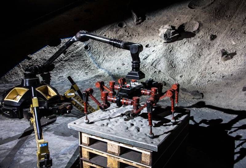 Missionsstart nach der Mondlandung: Der Rover „Sherpa“ dockt seinen zwei Meter langen Greifarm an Kletterroboter CREX an, um ihn aus dem Lander – hier durch Paletten simuliert – zu heben. (Bild: DKFI/Florian Cordes)