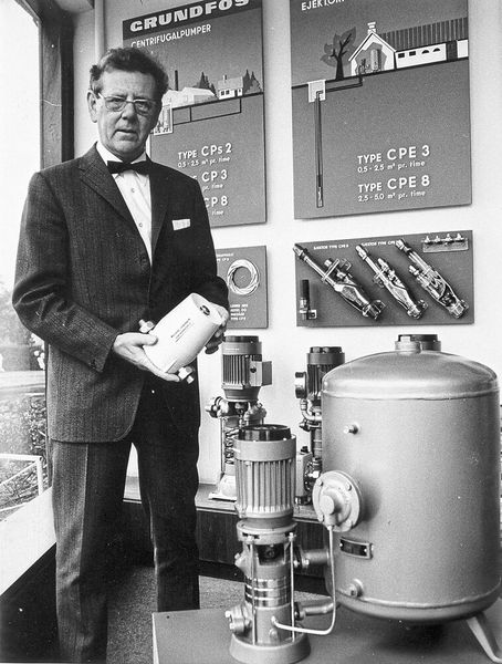 1958: Poul Due Jensen, company founder of Grundfos; in his hands he is holding the first VP32 heating circulation pump, and multi-stage CP pumps with a segment-based design can be seen in the background and on the right of the picture. (Grundfos)
