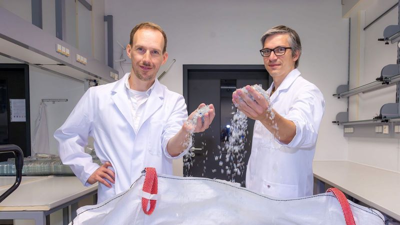 Dr. Ronny Frank (links) und Dr. Christian Sonnendecker vor einem Sack voll kleingehäckselten PET-Obstschalen, die darauf warten, mithilfe des Enzyms PHL7 in ihre chemischen Bausteine zerlegt zu werden.(Bild:  Swen Reichhold/Universität Leipzig)