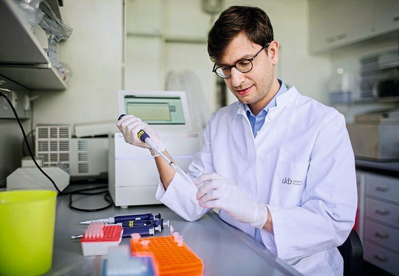 Prof. Dr. Jonathan Schmid-Burgk beim Pipettieren in einem Labor auf dem Campus des Universitätsklinikums Bonn (Universitätsklinikum Bonn / F. Heyder)