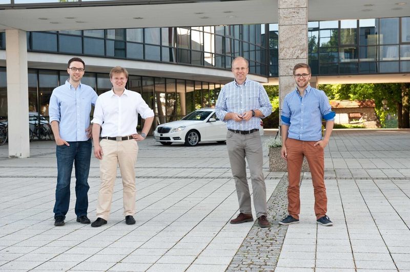 Neuer automatisierter Versuchsträger der Universität Ulm (im Hintergrund) und Kernentwicklungsteam (v.l.): Franz Gritschneder, Stefan Hörmann, Prof. Klaus Dietmayer und Alexander Scheel. (Bild: Uni Ulm)
