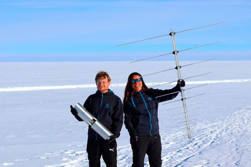 DESY-Physiker Christoph Welling (l.) und DESY-Physikerin Ilse Plaisier mit einer der Radioantennen des neuen Neutrino-Detektors auf Grönland. 
