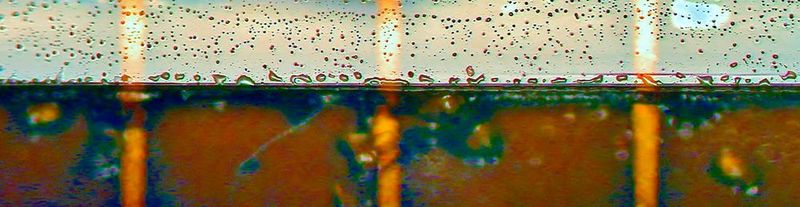 Das Bild zeigt in der Bildmitte senkrecht die Laminat-Kante. Unterhalb ist der Blick durch den gebondeten Optical Stack mit sichtbar gemachtem Flüssig-Kleber und oberhalb sieht man überschüssigen Kleber, der sich entlang der Lamminat-Kante zusammen gezogen hat. Das deutet auf eine schlechte Oberflächen-Benetzung - ein deutlicher Hinweis auf  eingebaute Probleme. Dunkelblaue Stellen zeigen massgeblich Blasenbildung (mehr ist schlechter) und rot-braune Stellen in unterschiedlichen Helligkeiten zeigen die Dichte-Verteilung des Klebers.  (Bild: Wammes und Partner)