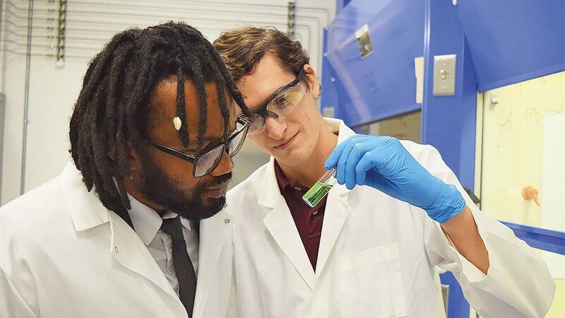 Dr. Abdoulaye Djire (left) and Denis Johnson (right) analyze a coloring solution after an experimental run. A coloring solution is created after each nitrogen reduction reaction experiment, and the level of ammonia produced is indicated by how green the solution turns after a waiting period.  (Texas A&M Engineering)