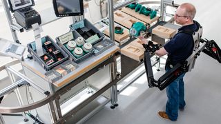 Dr. Konrad Stadler, Dozent für Regelungstechnik, Zürcher Hochschule für Angewandte Wissenschaften, demonstriert die Funktionsweise des Exoskeletts. Zu sehen ist die passive Unterstützung zum Heben schwerer Lasten. (Bild: Ludmilla Parsyak/Fraunhofer IAO)