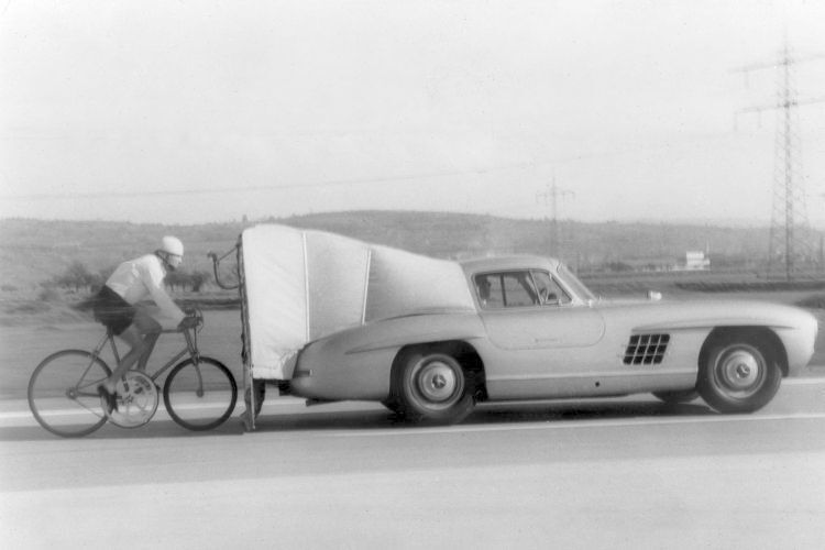 Rekordpartner: Hochleistungsautomobile mit dem Stern unterstützen auch andere sportliche Rekorde. Radrennfahrer José Meiffret erreicht 1962 im Windschatten eines Mercedes-Benz 300 SL „Gullwing“ (W 198) als erster Mensch 200 Stundenkilometer auf dem Fahrrad – gut ein halbes Jahrhundert, nachdem der Benz-200-PS-Rekordwagen als erstes Benzinautomobil diese magische Marke überschritten hatte. (Daimler)