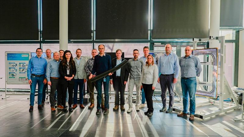 The TAVieDA project team: Christian Wolf, project manager at Airbus, presents an edge beam made of thermoplastic composite material. 4th from right: Dirk Herborg (DLR Project Management Agency); in the grey jacket: Dr. Rayk Fritzsche. 5th from left: Maxi Grobis. (Image:Fraunhofer IWU)