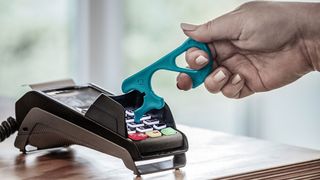 Mit dem vor Viren und Bakterien schützenden „Rehau Notouch“-Haken bekommt man eine praktische Greifhilfe aus Kunststoff, die nicht nur dem Corona-Virus unerwünschte Übersprungshandlungen vereitelt. Erfunden haben es diesmal keine Schweizer, sondern die Belegschaft von Rehau. Hier sieht man ihn im Einsatz beim berührungslosen Zahlen (fehlt jetzt nur noch geldlos als nächstes Feature!). (Rehau)