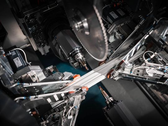 Das Bild zeigt ein in der servomotorischen Aufspannung befindliches Profil, das die beiden sich gegenüberliegenden 5-Achs-Fräsköpfe gleichzeitig bearbeiten können, sowie eine Säge von oben.(Bild:  Schirmer Maschinen)