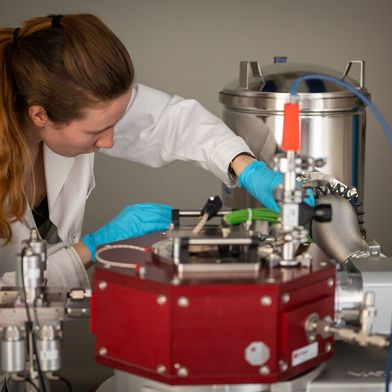 Johanna Byloff analysiert die Proben an der Beschichtungsmaschine des Empa-Spin-offs Swiss Cluster vor. (Bild: Empa)