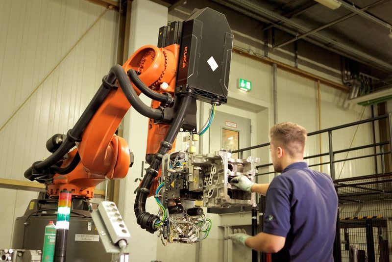 Der Mitarbeiter steuert den Roboter aus der KR Quantec Serie vom Typ KR 210 R2900 prime K mittels Joystick, um dann in einer angenehmen Körperhaltung die Bauteile auf Fehler zu prüfen. (Kuka)