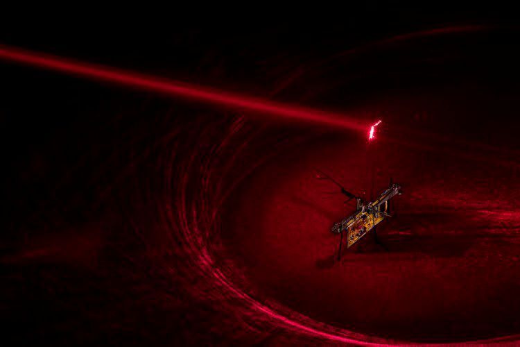 Roboterinsekt RoboFly: Um RoboFly mit Strom zu versorgen, richteten die Ingenieure einen unsichtbaren Laserstrahl (hier in rotem Laser) auf eine Photovoltaikzelle, die über dem Roboter angebracht ist und das Laserlicht in Strom umwandelt. (Mark Stone/University of Washington)