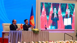 Nguyen Xuan Phuc (l), Premierminister von Vietnam, und Tran Tuan Anh, Handelsminister von Vietnam, applaudieren, während auf einer Leinwand Li Keqiang (l), Ministerpräsident von China, und Zhong Shan, Handelsminister von China, zu sehen sind. Nach achtjährigen Verhandlungen haben China und 14 andere asiatisch-pazifische Staaten das größte Freihandelsabkommen der Welt abgeschlossen. (Bild: Hau Dinh/AP/dpa)