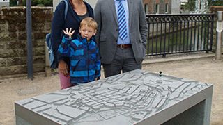 Max Jungeblodt, Geschäftsführer des Ideal-Werks in Lippstadt und Initiator des Projektes, mit Besuchern am Lippstädter Flutmodell. Die Reliefplatte aus Aluminium wurde von AHC technisch eloxiert. (Bild: AHC Oberflächentechnik)