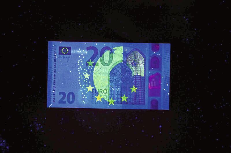 Unter einer UV-Lampe leuchten winzige Pigmente unserer Geldscheine in den verschiedensten „Europium“-Farben.