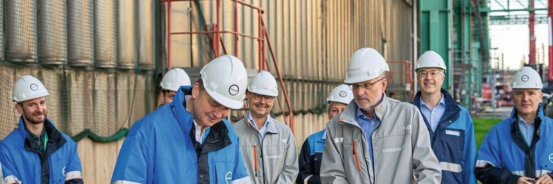 Alte Wärmewelt- trifft neue: Covestro-Produktionsleiter Daniel Koch unterzeichnet den Letter Of Intent zur gemeinsamen Wärmepumpen-Entwicklung mit Currentavor einem Kühlturm in Uerdingen.(Bild:  Covestro)