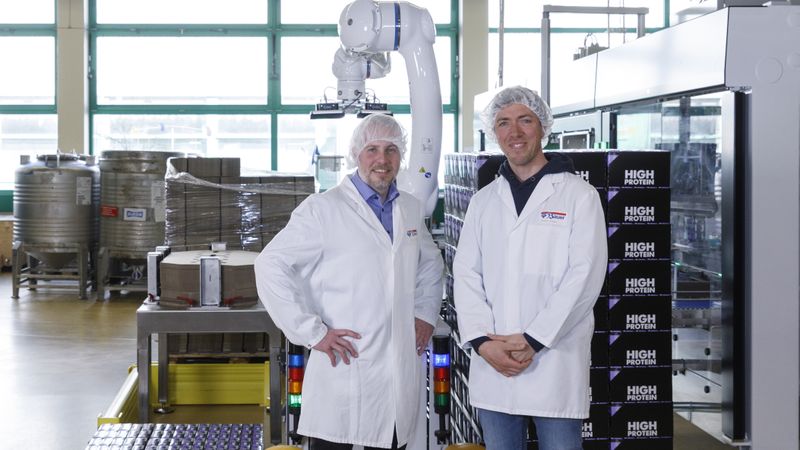 Ein starkes Trio: Hannes Langreiter von Profipack (links), Anton Weber von der Privatmolkerei Bauer und der Yaskawa-Cobot.(Bild:  Yaskawa Europe GmbH)