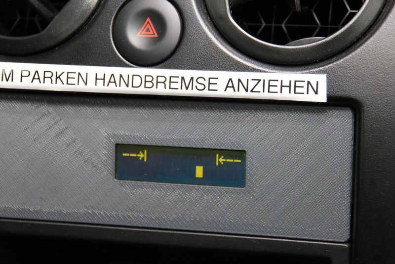 Im Armaturenbrett, unterhalb der mittleren Lüftungsöffnugen,  befindet sich im Vergleich zu anderen Elektrofahrzeugen, die über Stecker geladen werden, ein zusätzliches Instrument. Es zeigt  dem Fahrer an, ob er das Fahrzeug richtig oberhalb des Ladefeldes geparkt hat. (a)