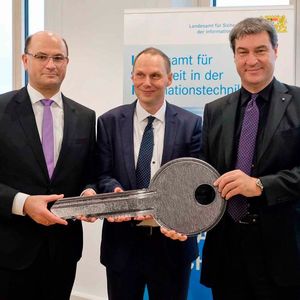 Staatsminister Dr. Markus Söder (r.), Staatssekretär Albert Füracker (l.) und Ministerialrat Daniel Kleffel, den kommissarischen Leiter des neuen Landesamts, bei der Schlüsselübergabe