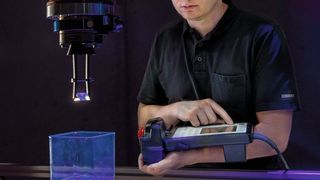 Max Schneckenburger, Masterand Maschinenbau, glättet die Oberfläche einer 3D-gedruckten Kunststoffoptik mit dem Robot-Dip-Coating-Verfahren. Dabei wird die Acrylat-Optik in ein Harzbad getaucht und unter UV-Licht ausgehärtet. (© Thomas Klink, Hochschule Aalen)