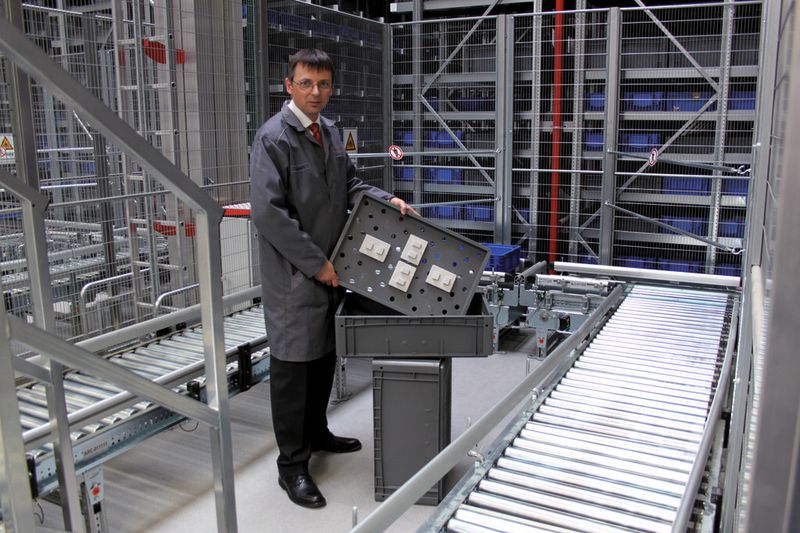 Dipl.-Wirtsch.-Ing. Jörg Reinelt, Logistikplanung Ersatzteile Porsche AG, zentrales Ersatzteillager Sachsenheim, zeigt ein Tablar mit vier aufgesteckten Fixierelementen. (Bild: Bito-Lagertechnik Bittmann GmbH)