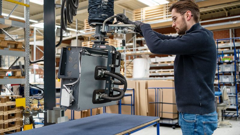 Ergonomische Palettierung: Der Heavylift 80 kg mit einem Seitenlifter hebt den Gebläsekonvektor vom Prüftisch und ermöglicht das sichere Umsetzen auf Palette oder Rollenbahn.(Bild:  Timmer GmbH)