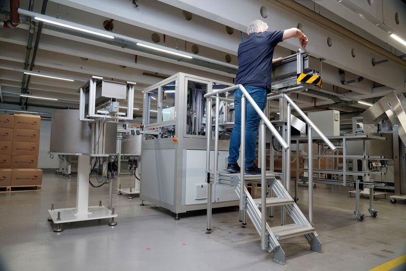 KM Packaging setzt im Montageprozess auch ein Treppen/Podeste-System von Item mit drei Stufen als Aufstiegshilfe ein. Dieses kommt zum Einsatz, wenn Maschinenbediener beispielsweise den seitlich in 2 Metern Höhe angebrachten Behälter mit den benötigten Einzelteilen auffüllen müssen. (Bild: Item)