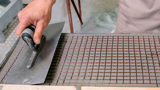 Im Otto-Mohr-Laboratorium der TU Dresden wird Feinbeton in einer dünnen Lage (dünner als 5 mm) auf eine Schalung aufgetragen. In diese Schicht wird ein Carbongelege eingelegt und mit einer Kelle leicht eingearbeitet. Anschließend wird das Gelege mit einer weiteren Schicht Feinbeton überdeckt. Der Vorgang wird so oft wiederholt bis die gewünschte Lagenanzahl erreicht ist (meist 2 bis 4 Lagen). (Jörg Singer)