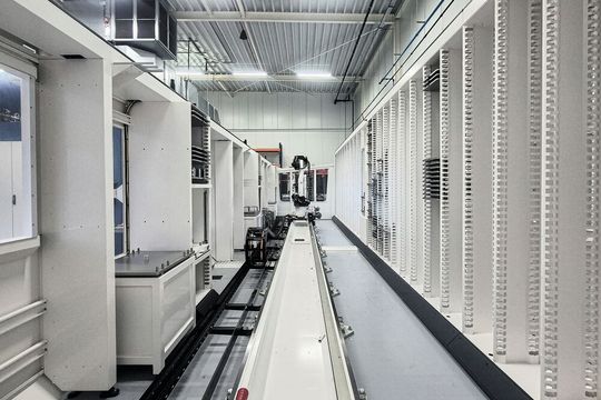 Die Fertigungszelle ist mit einem Roboter ausgestattet, der über ein Schienensystem Paletten und Werkstücke zwischen den verschiedenen Bearbeitungszentren und Stationen transportiert.(Bild:  Grob-Werke GmbH & Co. KG)