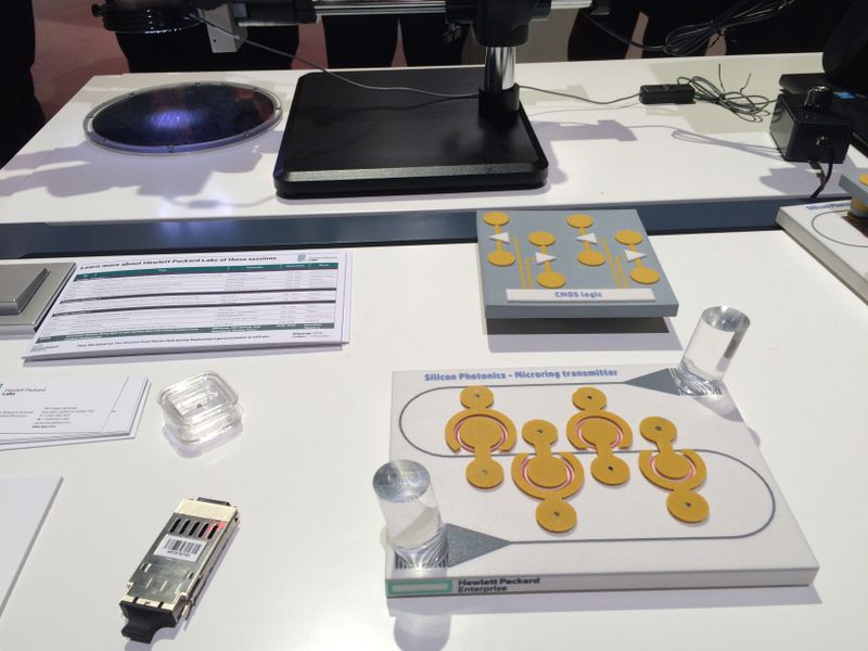 Hier auf dem Tisch liegt alles, was dafür notwendig ist: In der Plastikschachtel befindet sich der Chip in Originalgröße. rechts daneben zeigt ein Modell, wie diese Übersetzung funktioniert. Die beiden herausstehenden durchsichtigen Stäbe entsprechen den Glasfasern. Die Kreise tasten quasi den Lichtstrom ab und geben, solange dieser vorhanden ist, im Takt ein elektrisches Signal ab. Das Bauteil oberhalb ist für die umgekehrte Richtung verantwortlich.  (Ulrike Ostler)