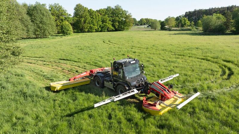 Zurück zu den Wurzeln: Der unmittelbar nach dem Zweiten Weltkrieg konzipierte Unimog war ursprünglich als rein landwirtschaftliches Fahrzeug gedacht. Er sollte einem zweiachsigen Traktor ähneln, aber vier gleich große Räder, Allradantrieb mit Differenzialsperren, schraubengefederte Portalachsen, geschützte Antriebswellen in Schubrohren, Trommelbremsen an allen Rädern und einen Leiterrahmen haben. Heute kommt er nur noch selten in der Landwirtschaft zum Einsatz, wie hier etwa als fahrende XXL-Sense. (Bild: Daimler Truck)