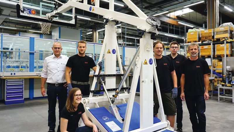 Rexroth-Antriebe für Basketballkörbe – Normalerweise verbindet man die Antriebs- und Steuerungstechnik von Bosch Rexroth mit industriellen Anlagen. Jetzt richtet Linear- und Steuerungstechnik des Unternehmens Basketballkörbe auf. Aus einem Ideenwettbewerb der FH Würzburg-Schweinfurt ist jetzt ein fahrbares Bedienpult entstanden, von dem aus ein einziger Helfer die Körbe mit elektromechanischen Zylindern aufrichtet, die von Bosch Rexroth stammen. (Bosch Rexroth)
