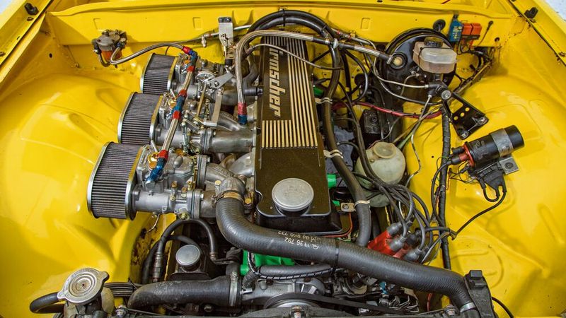 Ein Motorraum, von dem heutige Mechatroniker nur träumen können. Trotz circa 230 PS ist links und rechts des Aggregats noch jede Menge Platz. Beatmet wird der Sechszylinderreihenmotor mit seinem CIH-Zylinderkopf (Camshaft in Head: eine obenliegende Nockenwelle wirkt über Kipphebel auf die Ventile) aus Grauguss über drei Weber-Doppelvergaser. (Bild: Irmscher)