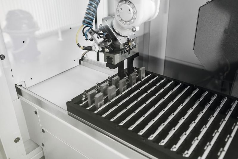 Die von  Medartis selbst konstruierte Werkstückpalette mit Vielfachaufnahmen stellt Titanrohlingen bereit beziehungsweise nimmt Fertigteile auf, wobei das Handling durch den Roboter komplett automatisiert ist.  (Medartis AG)