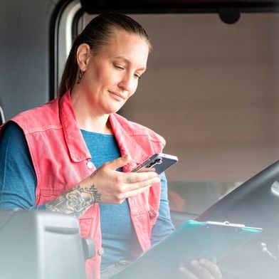 Eine Lkw-Fahrerin bucht eine Mautstrecke mit Toll-Now auf dem Smartphone. (Bild: Toll Collect)
