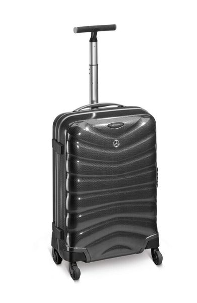 Koffer Firelite Spinner 55 aus Curv® in der Farbe Charcoal (Anthrazit) mit elastischen Kreuzspanngurten in der unteren Schale und mit Futterstoff bezogenem Raumteiler in der oberen Schale.  Leicht und leise laufende Rollen, dreiteiliges TSA-Schloss, Maße: (handgepäcktauglich) ca. 40 x 55 x 20 cm, Gewicht 1,95 kg, von Samsonite für Mercedes-Benz. Artikelnummer: B66951616. (Bild: Daimler)