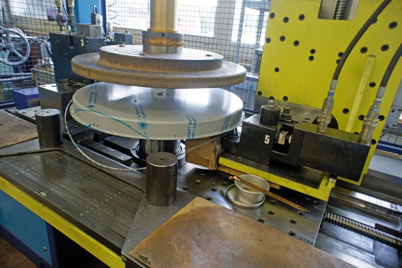 So entstehen die Waagschalen: Ein Werkstück ist zentral geklemmt und rotiert in der Maschine. Die ausgefransten Ränder des tiefgezogenen Blechteils werden geschnitten und gebördelt. (B&R)