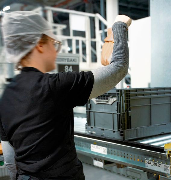 Einzigartig: Online bestellte Backwaren werden zeitnah zur Auslieferung in einer Bäckerei direkt im Logistikzentrum gebacken. Die Backstücke werden anschließend über Fördertechnik den teilautomatisierten Kommissionierarbeitsplätzen zugeführt. (Bild: Witron)