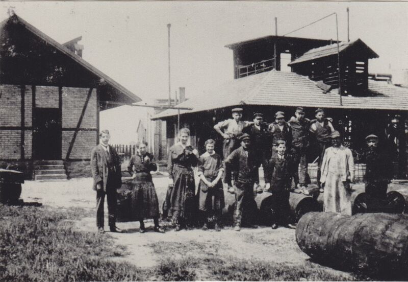 Das Rheinauer Werk in einer frühen Aufnahme um 1910: Rechts hinter der Belegschaft ist das hölzerne Freiluft-Produktionsgebäude zu sehen. (Bild: Rhein Chemie Rheinau)