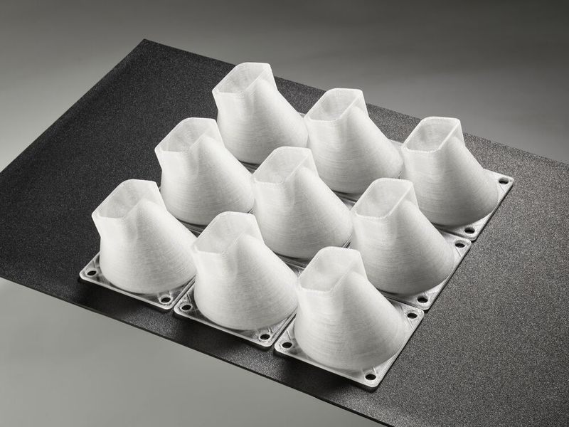 Am Stand von Arburg wurden mit einem Freeformer Luftkanäle aus dem für die Luft- und Raumfahrt freigegebenen Originalmaterial PC Lexan 940 produziert. Die Kleinserien aus je neun Funktionsbauteilen entstehen in einer Bauzeit von rund 24 Stunden. (Bild: Arburg)