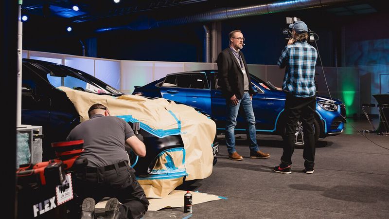 Am Vormittag startete APZ mit der Live-Aufbereitungsshow: Die Aufgabe war, zwei Fahrzeuge mit Gebrauchsspuren innerhalb von fünf Stunden mit Smart Repair und optischer Aufbereitung so zu bearbeiten, dass der Minderwert von jeweils circa 1.600 Euro ausgeglichen wird. Die Dekra hatte vorab ein Bewertungsgutachten erstellt. APZ-Geschäftsführer Boris Quitmann berichtete mehrmals am Tag live ins Kongressplenum, wie der Stand der Dinge ist. (Bild: Stefan Bausewein)